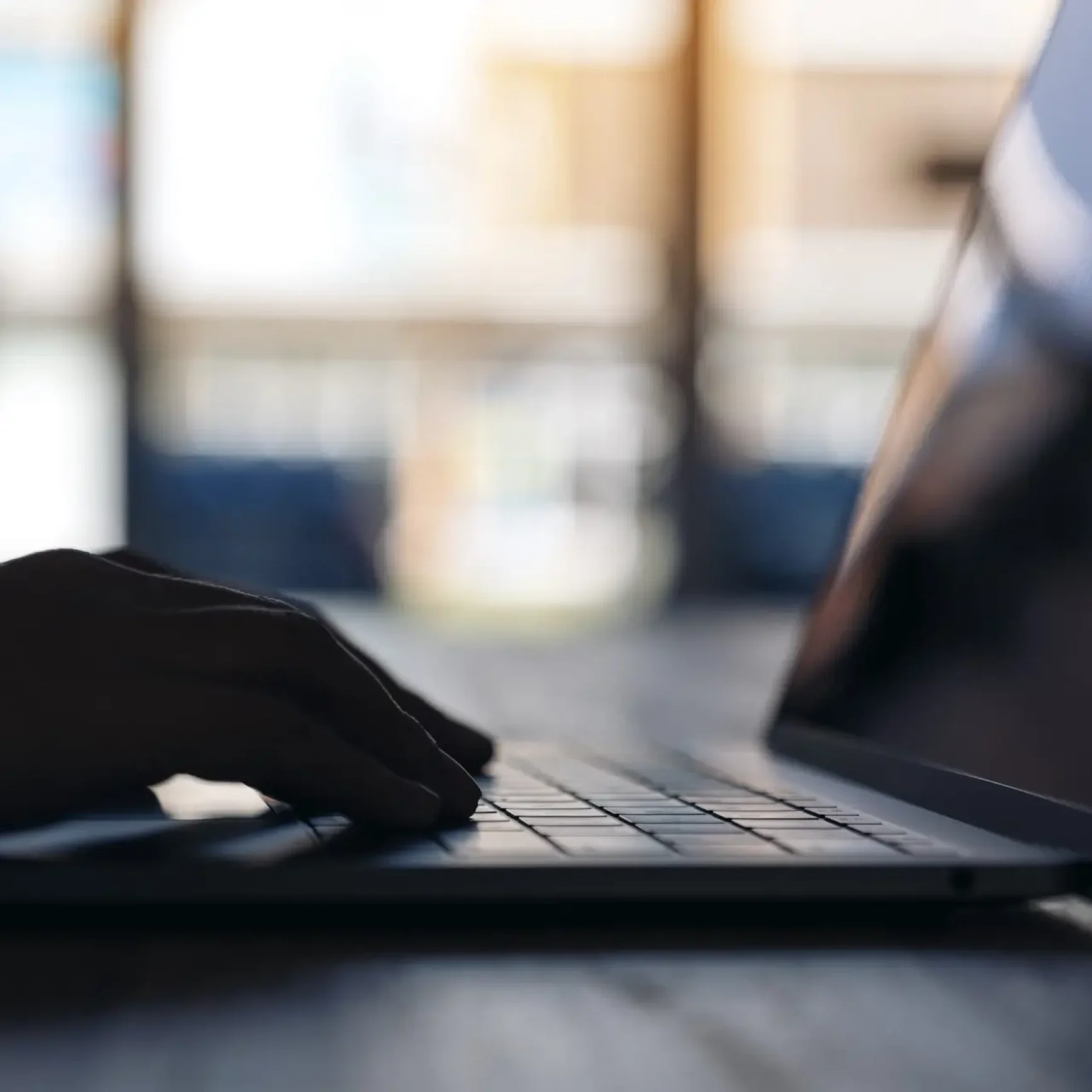 Closeup image of hand using and typing on laptop keyboard in cafe